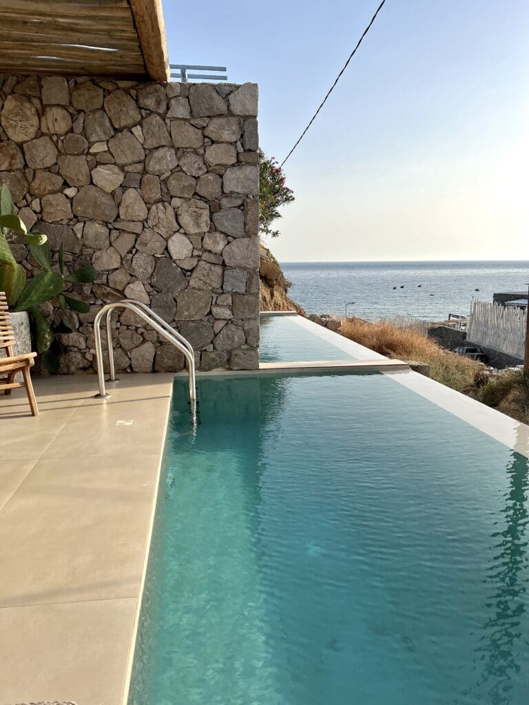 View of a room with a private pool looking onto the parking area with partial sea views in Milos Greece