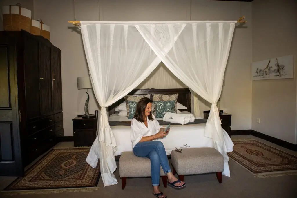 Bed with canopy and lady sitting on bed reading a magazine