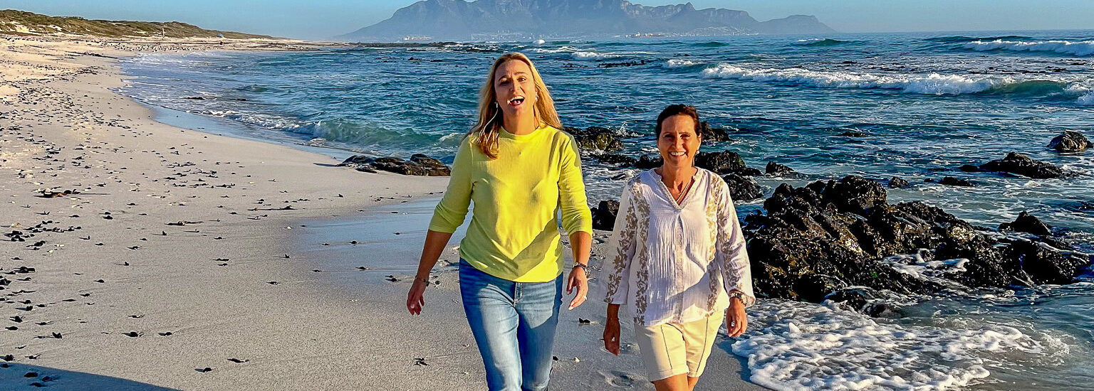 Two ladies walking along the beach with Table Mountain in the backdrop