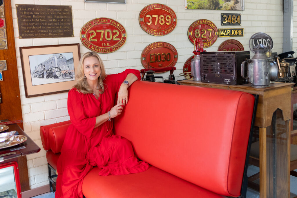 Lady in red dress sitting on a red coach at Rovos Rail's museum