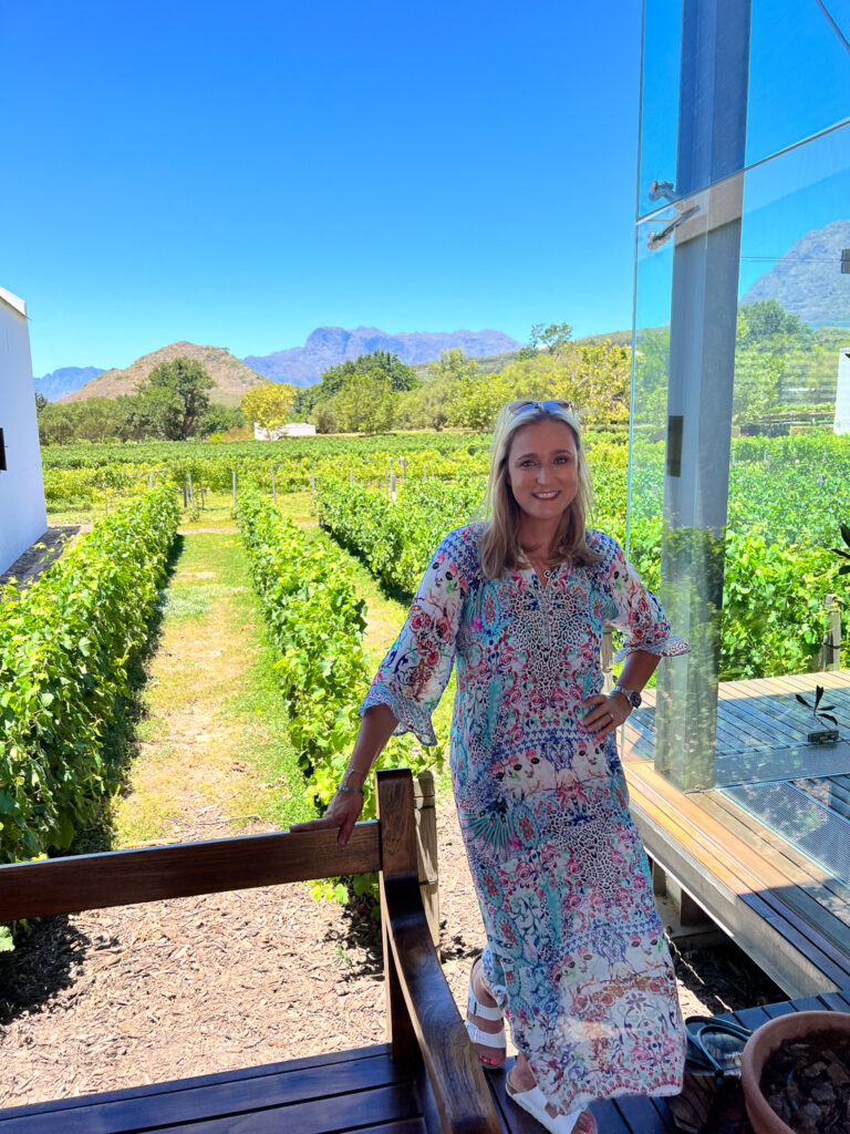 Bernie at the entrance of Babylonstoren'stasting room with vinyards in the back drop